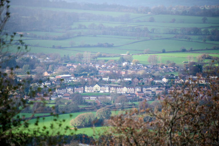 View over the town of Ottery St Mary surrounded by green fields on a hazy day.